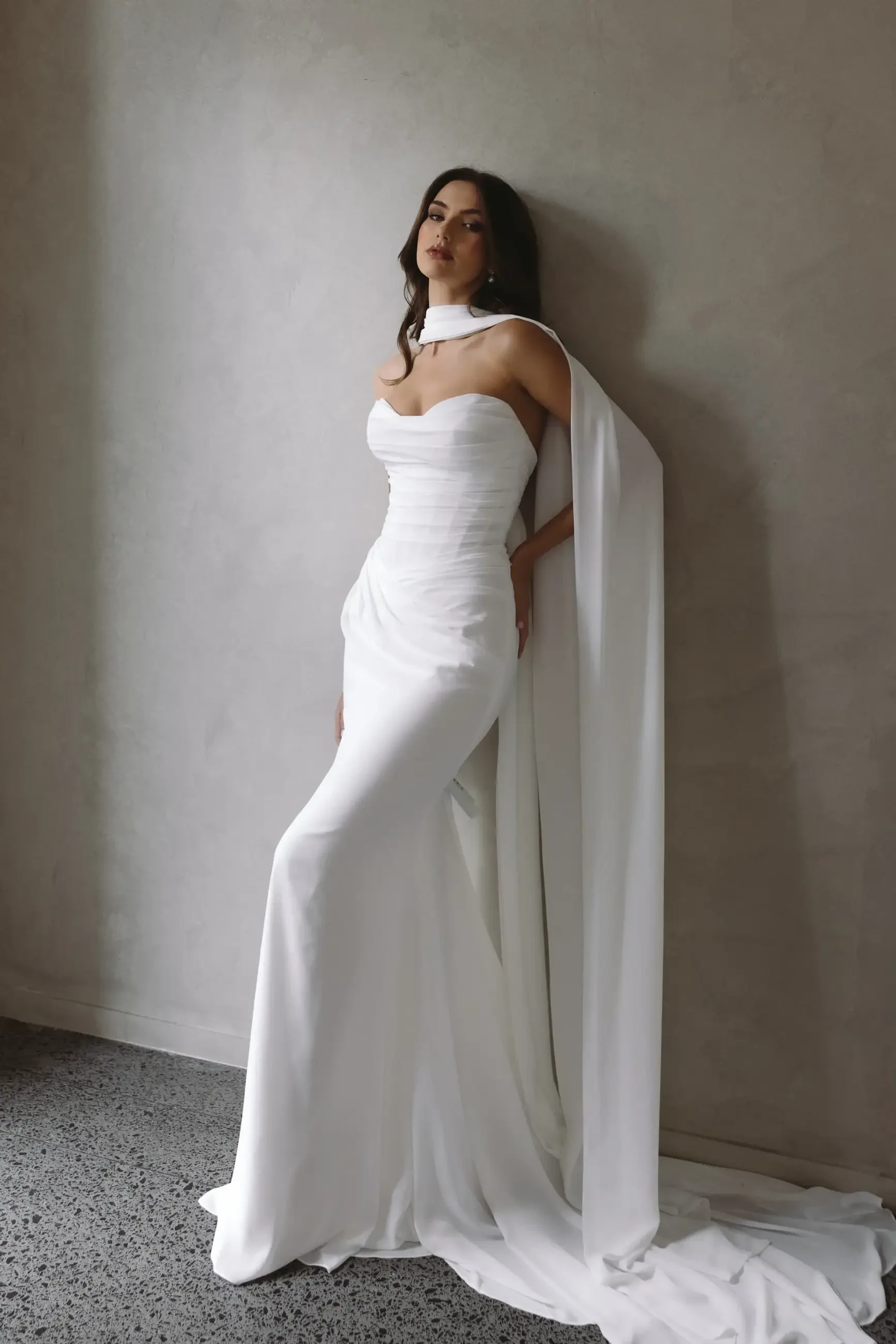 model is wearing a strapless fit and flare wedding dress with a neck scarf