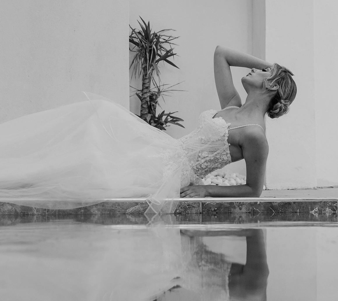 Photo of the model wearing bridal gown and posing near the water